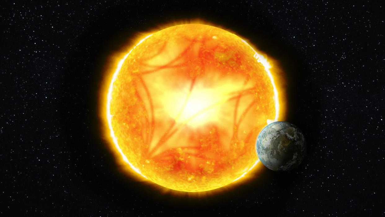  A small blue green planet hangs in front to the side of a bright orange yellow sun. 