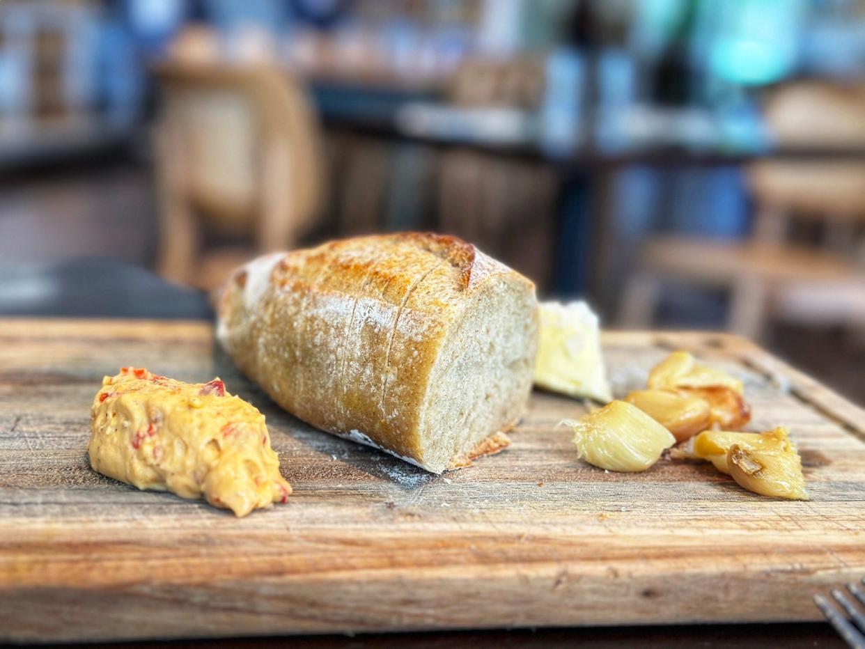 A crusty loaf of fresh sourdough bread is served with roasted garlic and pimento cheese at Colab Kitchen restaurant in Stuart.