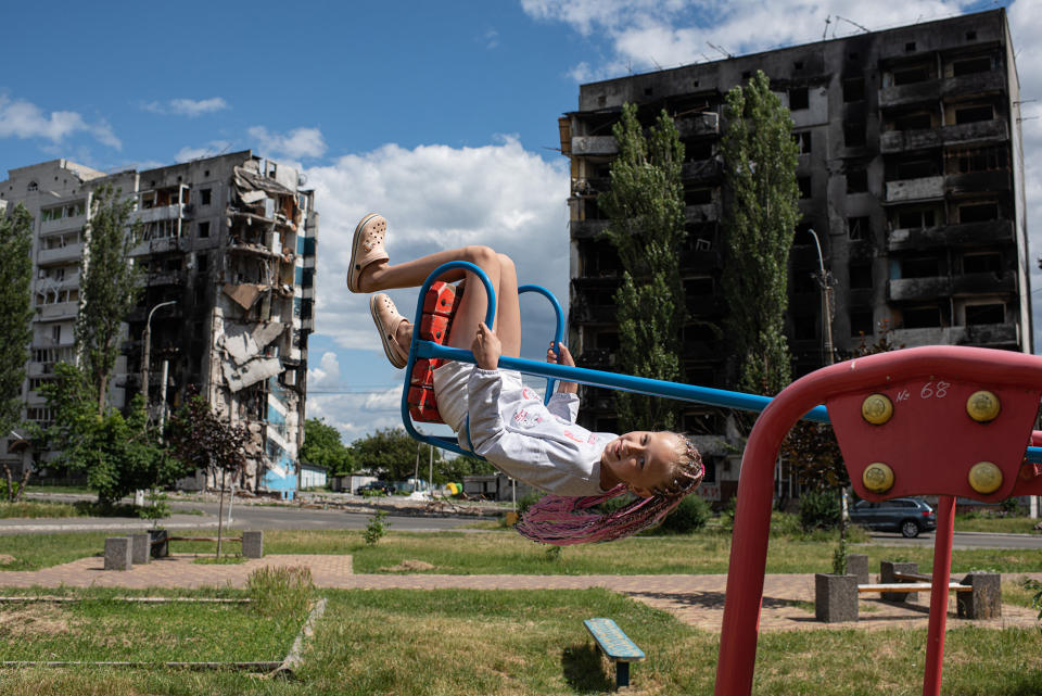 A girl is seen on a swing next to a shelled apartment building in Borodianka, Ukraine, on June 15, 2022.