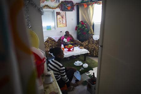 Angesom Solomon (rear), a 28-year-old African migrant from Eritrea, sits with his wife and son in their living room at their home in Tel Aviv November 30, 2013. REUTERS/Ronen Zvulun