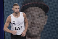 Edgars Tocs, of Latvia, runs past a huge image of himself as he arrives a men's beach volleyball semifinal match against Norway at the 2020 Summer Olympics, Thursday, Aug. 5, 2021, in Tokyo, Japan. (AP Photo/Petros Giannakouris)