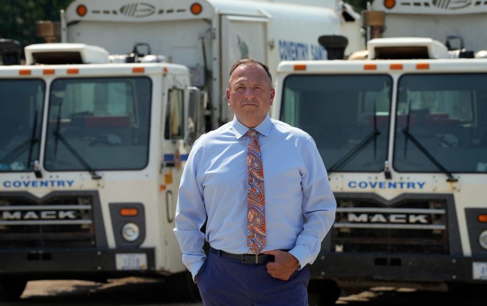 Coventry Town Manager Daniel Parrillo stands in front of two of the town's remaining trash disposal trucks at Town Hall. Four trucks in Coventry's nine-vehicle fleet have been out of service.