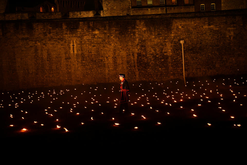 <p>A Yeoman of the Guard is seen amongst lit torches, part of the installation ‘Beyond the Deepening Shadow’ at the Tower of London, in London, Britain, November 7, 2018. (Photo from Reuters/Dylan Martinez) </p>