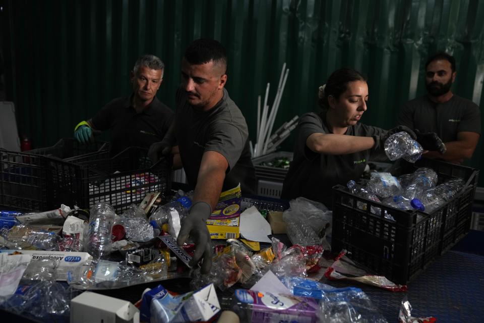 Recycle plant workers crew members separate waste on a sorting bench on the Aegean Sea island of Tilos, southeastern Greece, Monday, May 9, 2022. When deciding where to test green tech, Greek policymakers picked the remotest point on the map, tiny Tilos. Providing electricity and basic services, and even access by ferry is all a challenge for this island of just 500 year-round inhabitants. It's latest mission: Dealing with plastic. (AP Photo/Thanassis Stavrakis)