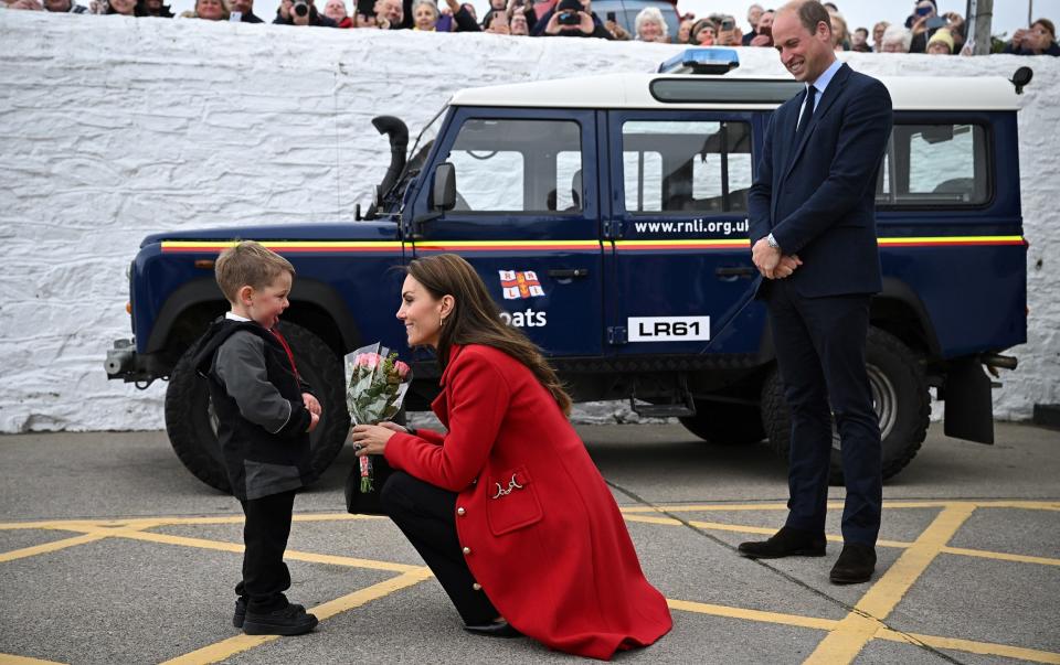 The Prince of Wales looks on as his wife the Princess of Wales is presented with a posy of flowers by four-year-old Theo Crompton during their visit to the RNLI - Paul Ellis/ WPA Pool / Getty Images/ Getty Images Europe