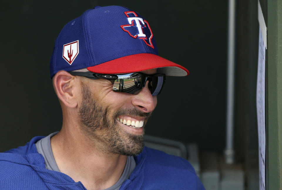 FILE - In this March 6, 2019, file photo, Texas Rangers manager Chris Woodward smiles as he talks with other coaches prior to a spring training baseball game against the San Francisco Giants, in Surprise, Ariz. First-year Texas manager Chris Woodward loves that the expectations are higher. At 42-36 just shy of the midpoint of the season, the Rangers haven’t lost any of their eight series over the past month. (AP Photo/Ross D. Franklin, File)