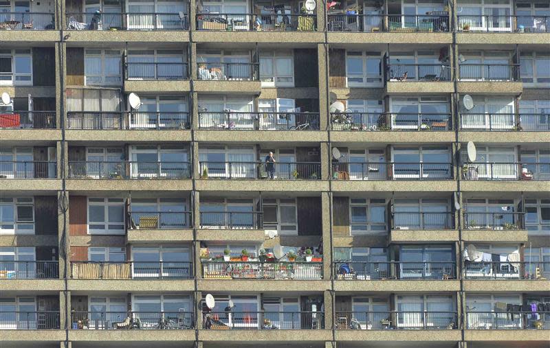 A man stands on a balcony (C) in a residential high rise block of flats in North Kensington in central London October 8, 2013. REUTERS/Toby Melville