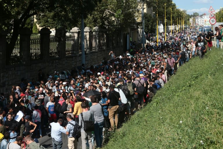 Hundreds of migrants walk after leaving the transit zone of the Budapest main train station, on September 4, 2015