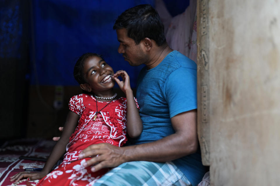 Jerifa Islam spends time with her father Jaidul Islam at a neighbor's home in a poor neighborhood in Bengaluru, India, Tuesday, July 19, 2022. A flood in 2019 in the Darrang district of India's Assam state started Jerifa Islam, her brother Raju and their parents on a journey that led the family from their Himalayan village to the poor neighborhood. (AP Photo/Aijaz Rahi)