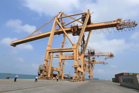 Workers walk under cranes damaged by air strikes at the port of Hodeida, Yemen April 1, 2018. Picture taken April 1, 2018. REUTERS/Abduljabbar Zeyad