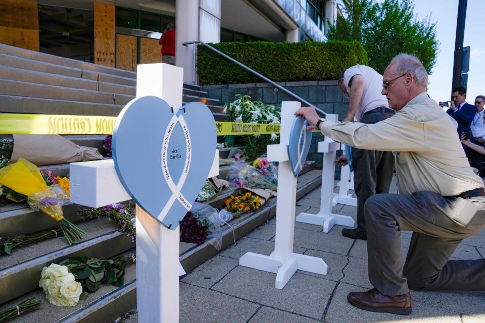 Wayne Kolweier, with Lutheran Church Charities from Northbrook, Illinois, on Tuesday, April 11, 2023 hangs a heart for one of the shooting vicitims outside the Old National Bank a day before that left six dead, including the shooter, and another 8 injured.