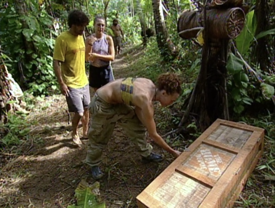 Jerri Manthey opens a crate with The Home Depot written on it while Ethan Zahn and Jenna Lewis look on