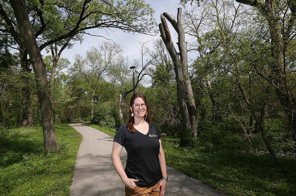 Gabriele Edwards, the Ames city forester, takes a moment to pose with her most trusted constituents, the trees of Brookside Park on Thursday, May 11, 2023. Over her shoulder is a silver maple tree that was converted into wildlife habitat rather than being completely taken down for safety.