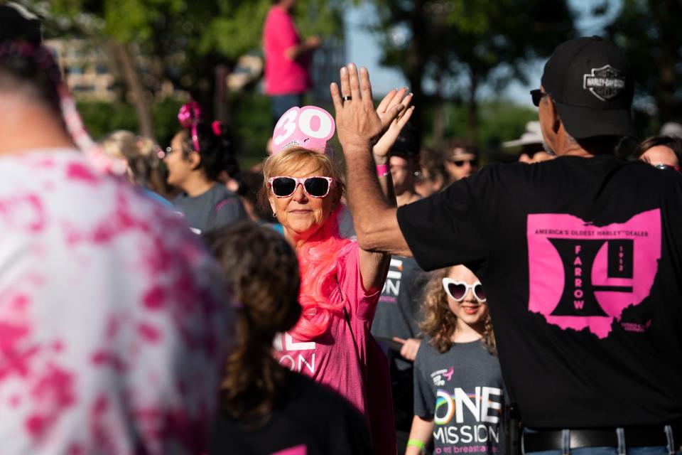 High-fives are thrown Saturday at thunder alley at the start of the annual Komen Columbus Race for the Cure, which is back in person, after a two-year absence because of COVID-19.