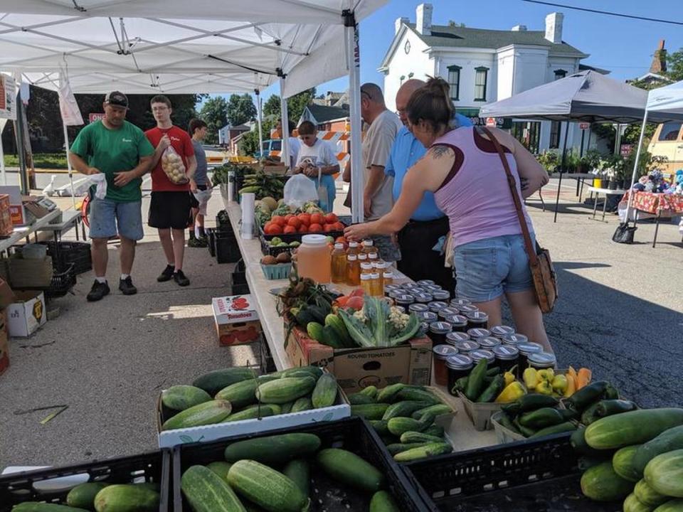 Visitors look over produce at a stand at Old Town Farmers Market on South Charles Street in Belleville in 2019.