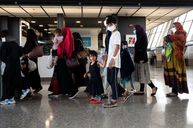 Afghan refugees are escorted to a waiting bus after arriving and being processed at Dulles International Airport on Aug. 23. (Photo: ANDREW CABALLERO-REYNOLDS via Getty Images)