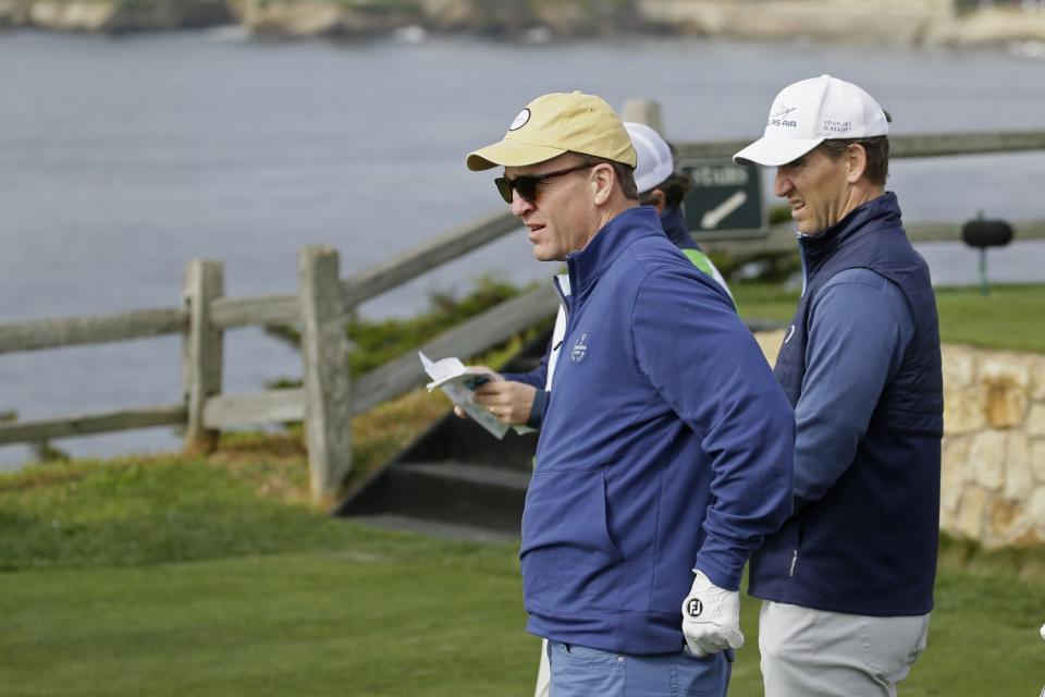 Peyton Manning, left, and brother Eli look over the seventh green of the Pebble Beach Golf Links in 2020.