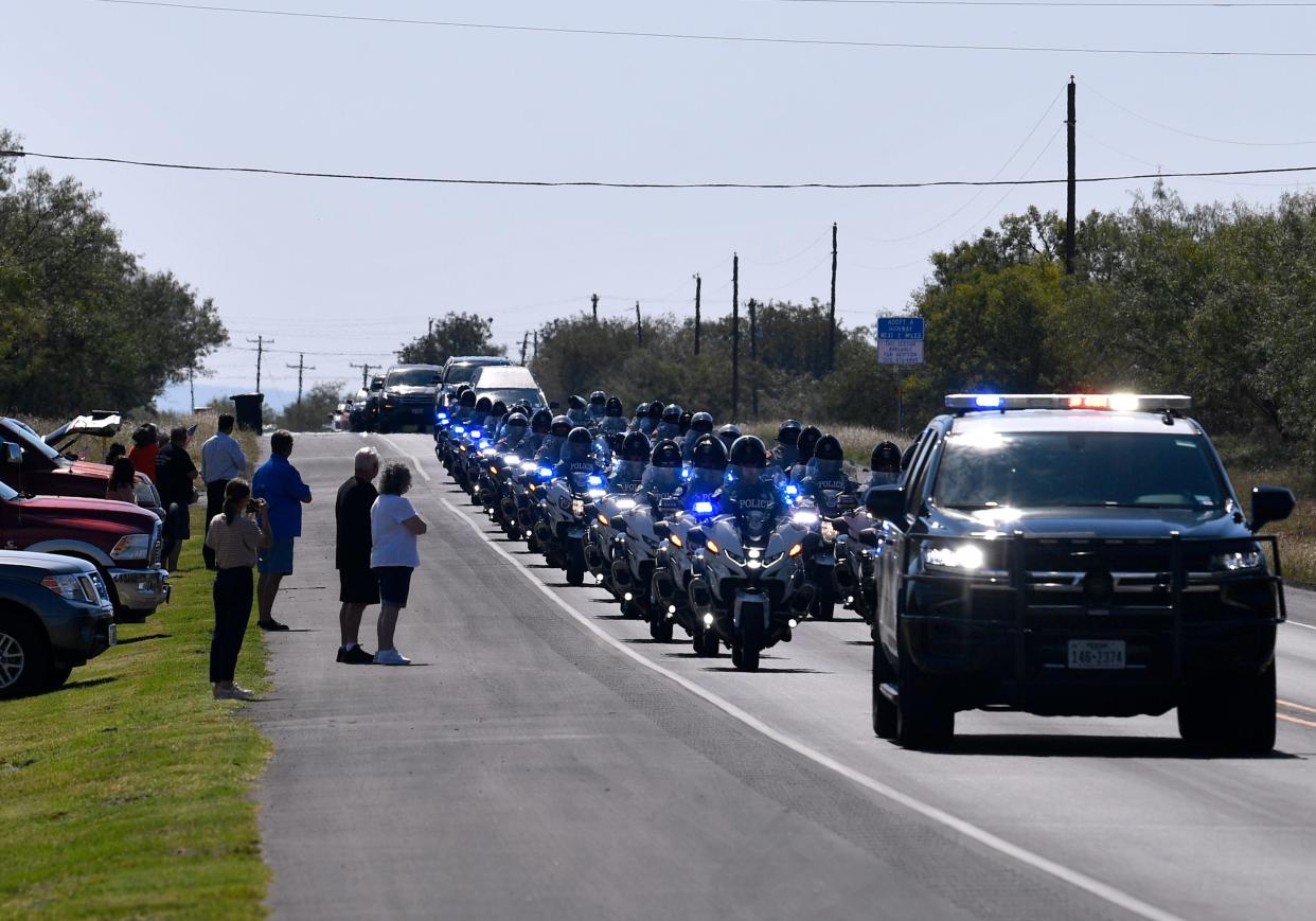 People line up on the shoulder of FM600 as the procession carrying the body of Austin police officer Anthony Martin passes on its way to Texas State Veterans Cemetery at Abilene Tuesday. A former Dyess Air Force Base airman, Martin died in the line of duty Sept. 23.