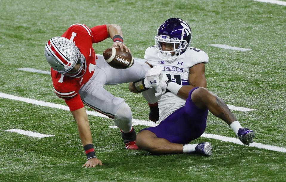 Northwestern Wildcats defensive back Cameron Mitchell (21) sacks Ohio State Buckeyes quarterback Justin Fields (1) during the first quarter of the Big Ten Championship football game at Lucas Oil Stadium in Indianapolis on Saturday, Dec. 19, 2020. 