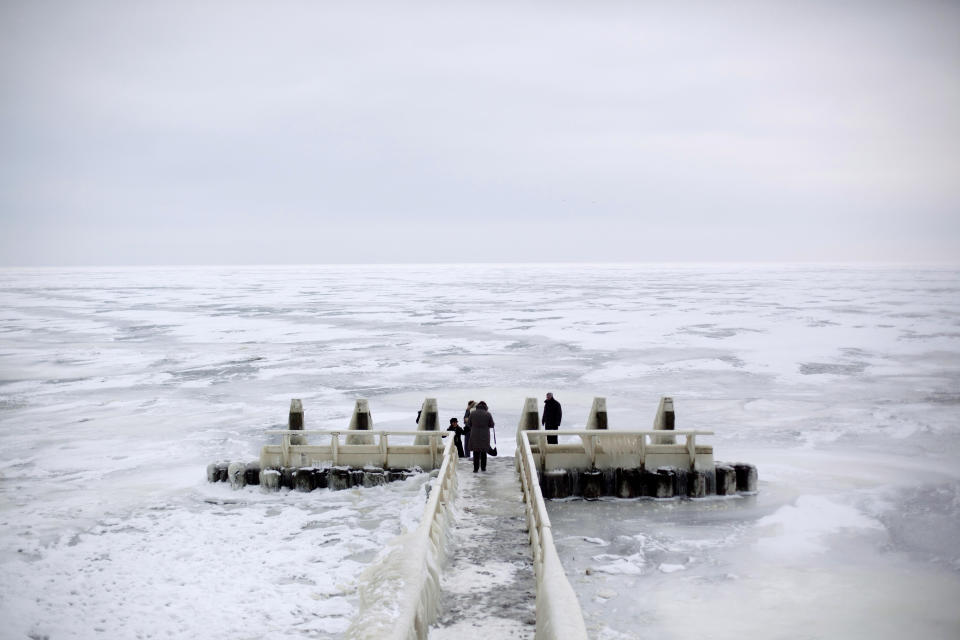 In this image taken Thursday Feb. 9, 2012, Tourists admire the frozen IJsselmeer inland sea on Afsluitdijk, a dike closing off the Wadden sea and North Sea from IJsselmeer inland sea, northern Netherlands. Rising in a thin line through the surface of waters separating the provinces of North Holland and Friesland, the 87-year-old Afsluitdijk is one of the low-lying Netherlands' key defenses against the sea. With climate change bringing more powerful storms and rising sea levels, it's getting a major makeover. (AP Photo/Peter Dejong)