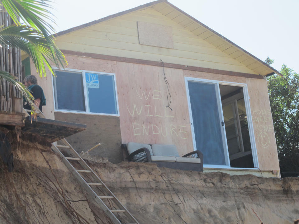 "We will endure" is scrawled on the wall of a house damaged by severe beach erosion in the Rocky Point neighborhood of Oahu's North Shore in Haleiwa, Hawaii on Tuesday, Dec. 31, 2013. Some property owners want to be able to install a seawall or something similar to protect their property, but scientists say doing so could lead the sand on the nearby coastline _ including Sunset Beach, home to some of the world’s top surfing contests _ to disappear. (AP Photo/Audrey McAvoy)