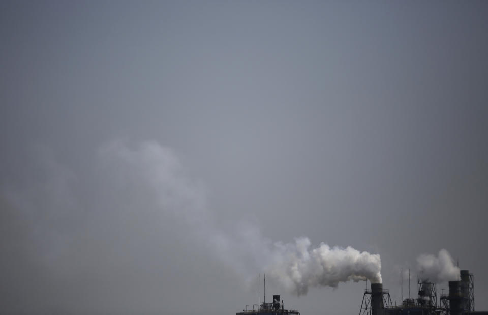 Smoke is discharged from chimneys at a plant in Tokyo, Tuesday, March 25, 2014. Along with the enormous risks global warming poses for humanity are opportunities to improve public health and build a better world, scientists gathered in Yokohama for a climate change conference said Tuesday. (AP Photo/Eugene Hoshiko)