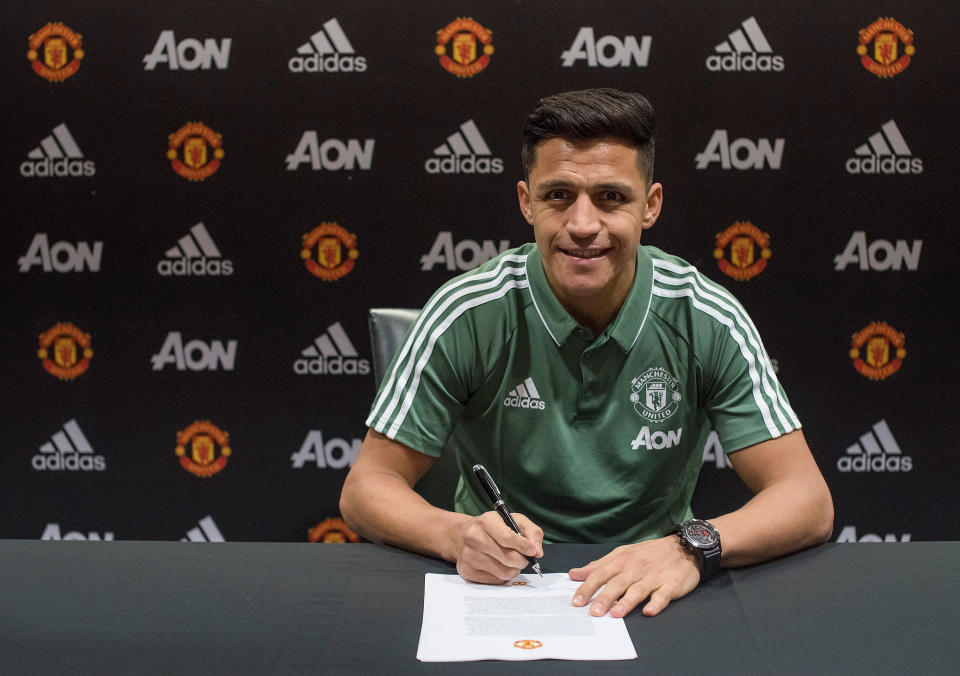 Alexis Sanchez poses while putting pen to paper as part of his Manchester United unveiling. (Getty)