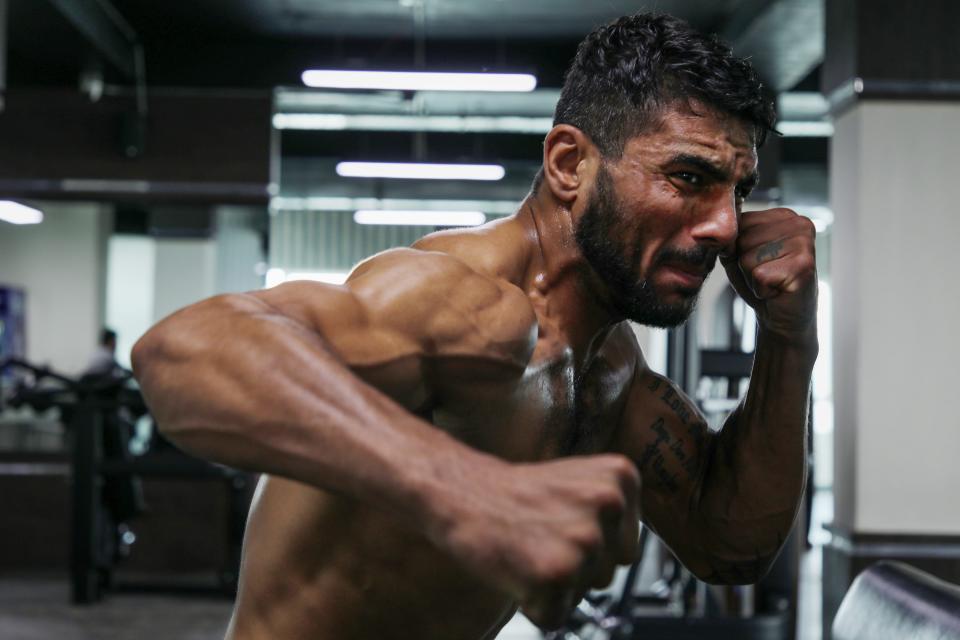 A close-up of a shirtless man shadowboxing.