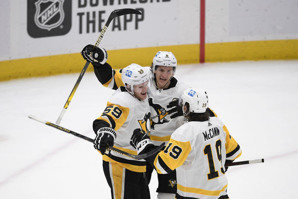 Pittsburgh Penguins left wing Jake Guentzel (59) celebrates his overtime goal with left wing Jared McCann (19) and defenseman John Marino (6) during an NHL hockey game against the Washington Capitals, Thursday, April 29, 2021, in Washington. The Penguins won 5-4. (AP Photo/Nick Wass)