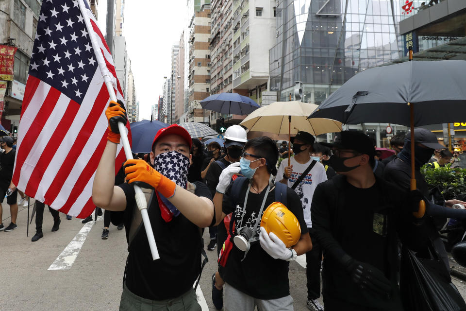 A protester carries a U.S. flag as they march through the Mong Kok neighborhood during a demonstration in Hong Kong, Saturday, Aug. 3, 2019. Hong Kong protesters ignored police warnings and streamed past the designated endpoint for a rally Saturday in the latest of a series of demonstrations targeting the government of the semi-autonomous Chinese territory. (AP Photo/Vincent Thian)