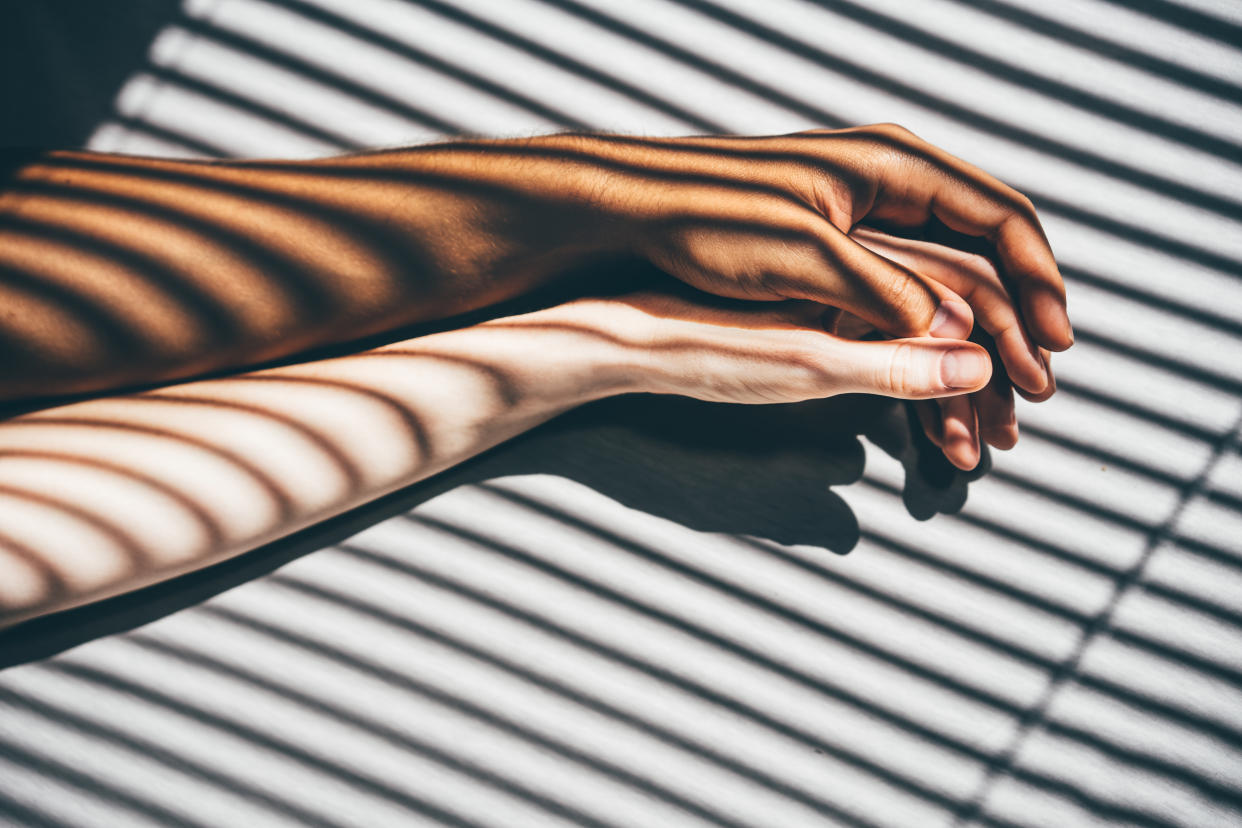 Interracial couple holding hands on the bed.