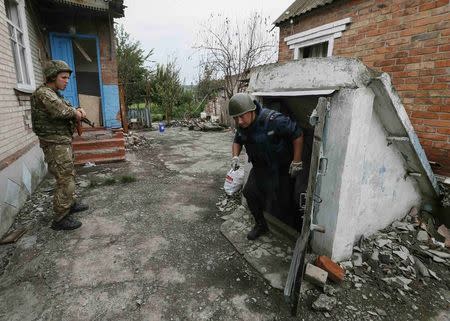 A sapper (R) checks a building as a member of the Ukrainian police special task force "Kiev-1" stands guard outside in the eastern Ukrainian village of Semenovka, near Sloviansk, July 14, 2014. REUTERS/Gleb Garanich