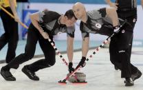 Canada's second E. J. Harnden (L) and vice Ryan Fry sweep ahead of a stone ahead of their men's curling semifinal game against Britain at the 2014 Sochi Olympics in the Ice Cube Curling Center in Sochi February 19, 2014. REUTERS/Ints Kalnins (RUSSIA - Tags: OLYMPICS SPORT CURLING)