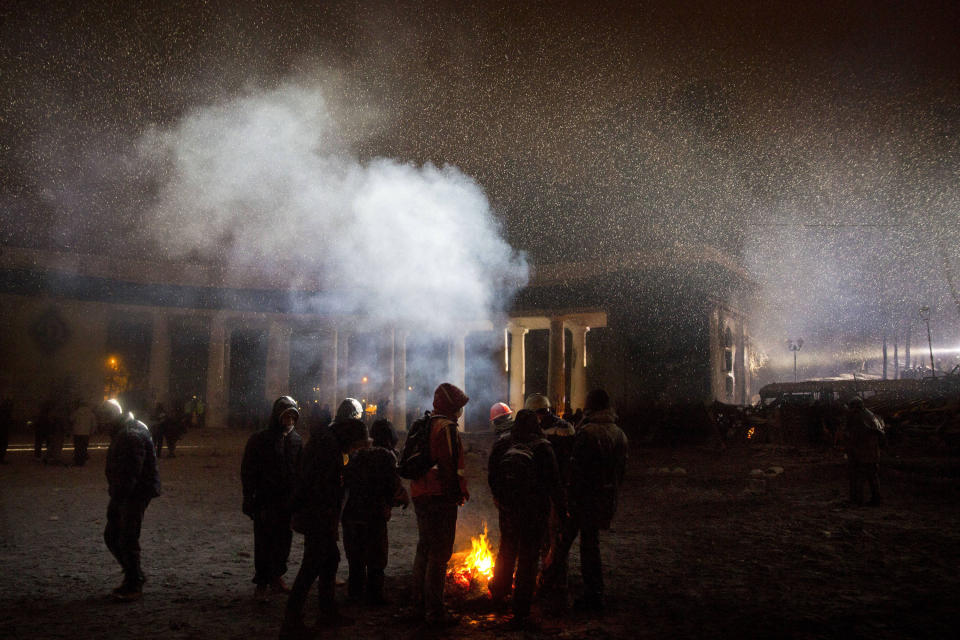 Protesters warm themselves behind the barricade during clashes with police in central Kiev, Ukraine, early Wednesday, Jan. 22, 2014. The mass protests in Kiev, the capital, erupted after Ukrainian President Viktor Yanukovych spurned a pact with the European Union in favor of close ties with Russia, which offered him a $15 billion bailout. (AP Photo/Evgeny Feldman)