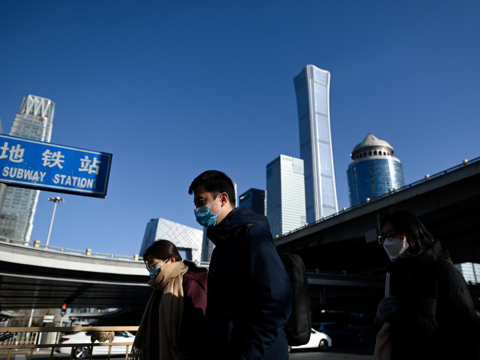 People wearing face masks walk in the central business district of Beijing on Monday (AFP via Getty Images)