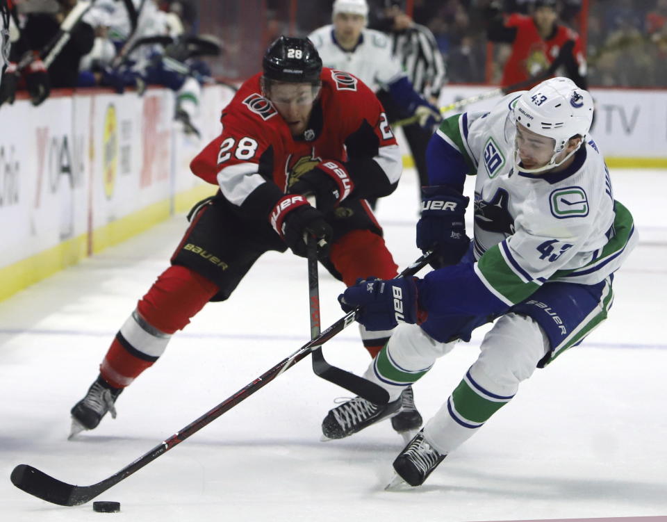 Ottawa Senators right wing Connor Brown (28) and Vancouver Canucks defenseman Quinn Hughes (43) battle for the puck during second-period NHL hockey game action in Ottawa, Ontario, Thursday, Feb. 27, 2020. (Fred Chartrand/The Canadian Press via AP)