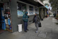 Lynnette White, right, greets a man outside of a market while interviewed in San Francisco, Tuesday, Feb. 16, 2021. The pandemic has sparked a surge of online shopping across all ages as people stay away from physical stores. But the biggest growth has come from consumers 65 and older. (AP Photo/Jeff Chiu)
