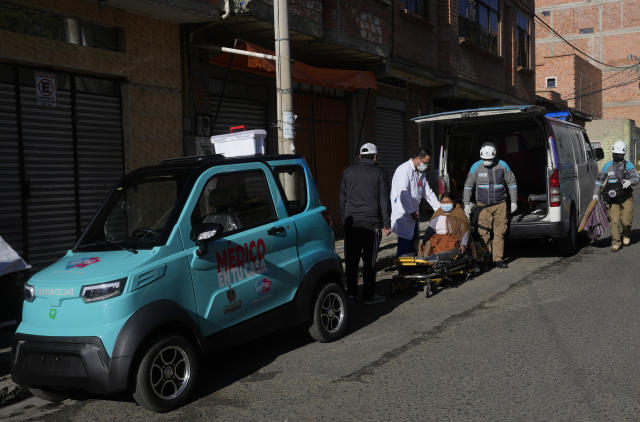 Dr. Carlos Ortuno tends to Juana Velasco flanked by a Bolivian-made, Quantum electric car and an ambulance, in La Paz, Bolivia, Wednesday, May 3, 2023. Velasco woke up feeling her heart racing and called Medico en tu Casa, a local program that sends doctors to people's homes. Soon after, Ortuno boarded the Quantum electric car and made his way to her home. Upon evaluating the patient, he called a local ambulance service to help transfer Velasco to the nearest hospital. (AP Photo/Juan Karita)