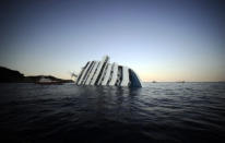 A handout aerial view taken and released on January 14, 2012 by Italian Guardia de Finanza shows the Costa Concordia, after the cruise ship ran aground and keeled over off the Isola del Giglio, on late January 13. Three people died and several were missing after the ship with more than 4,000 people on board ran aground sparking chaos as passengers scrambled to get off. The ship was on a cruise in the Mediterranean, leaving from Savona with planned stops in Civitavecchia, Palermo, Cagliari, Palma, Barcelona and Marseille," the company said. AFP PHOTO/ HO/ ITALIAN GUARDIA DE FINANZA