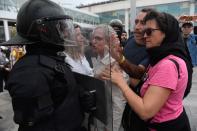 Uno de los agentes se protege mientras es increpado por varias personas (Photo by JOSEP LAGO/AFP via Getty Images)