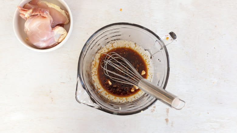 whisking chicken marinade in measuring cup