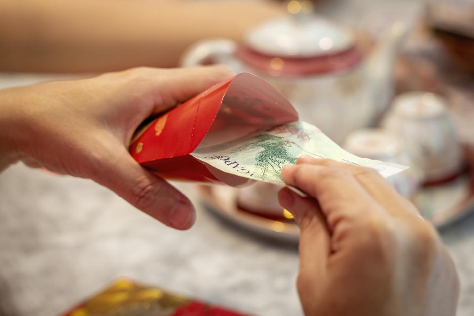 Close-up of hands preparing Chinese New Year (CNY) red packets during Chinese New Year festive period. (PHOTO: Getty)
