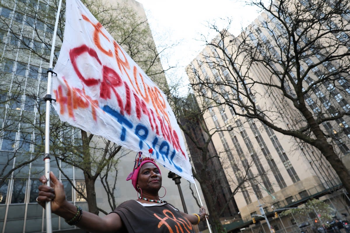 A protester holds a banner against Donald Trump outside the courthouse (REUTERS)