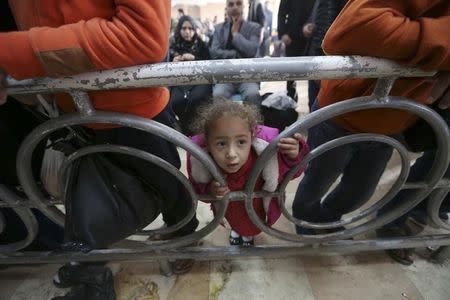 A Palestinian girl looks through a barricade as she waits with her family for a travel permit to cross into Egypt, at the Rafah crossing between Egypt and the southern Gaza Strip, March 10, 2015. REUTERS/Ibraheem Abu Mustafa