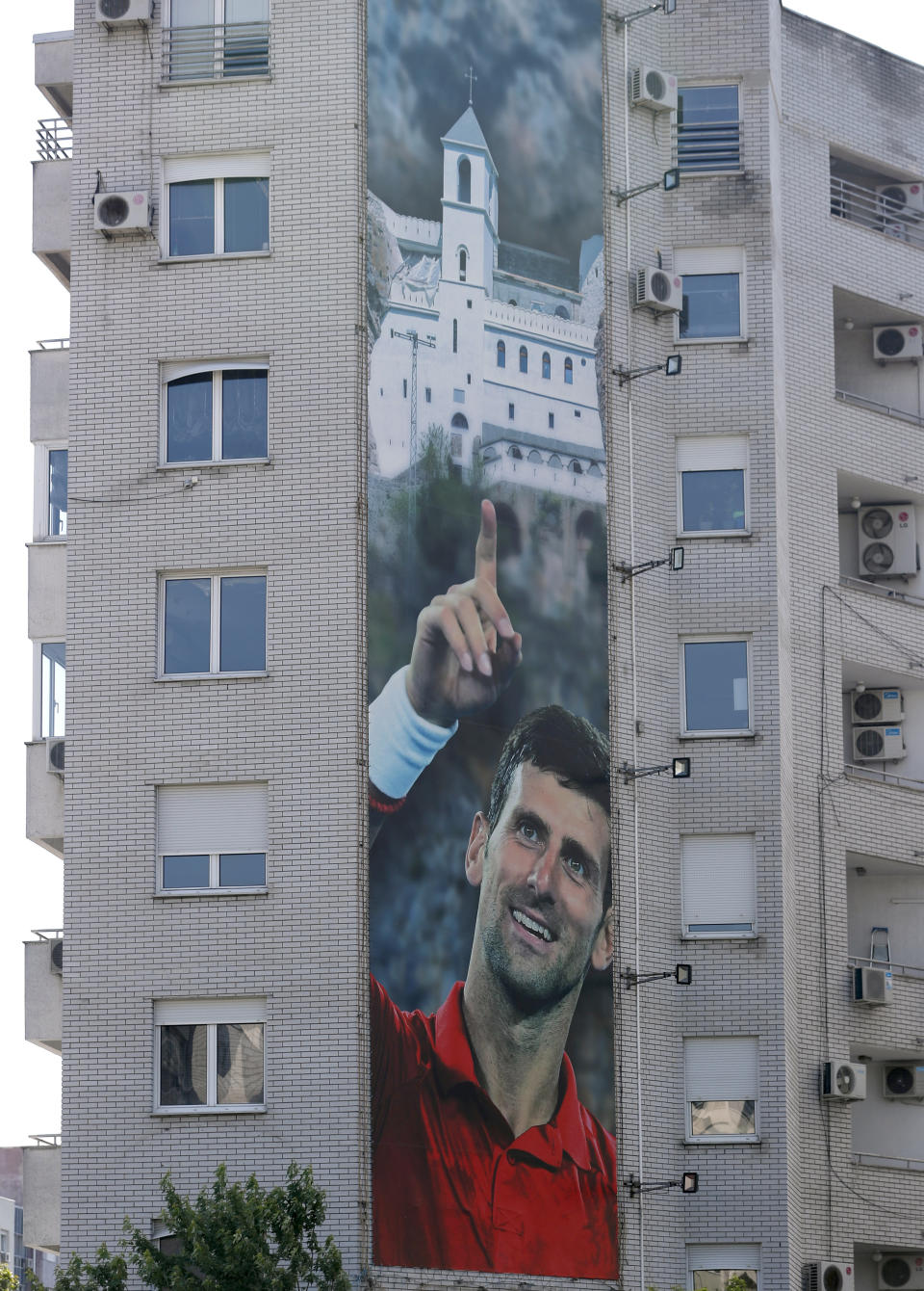 A billboard depicting Serbian tennis player Novak Djokovic and the Christian Orthodox monastery of Ostrog is seen on a building in Belgrade, Serbia, Wednesday, June 24, 2020. Djokovic has tested positive for the coronavirus after taking part in a tennis exhibition series he organized in Serbia and Croatia. The top-ranked Serb is the fourth player to test positive for the virus after first playing in Belgrade and then again last weekend in Zadar, Croatia.(AP Photo/Darko Vojinovic)