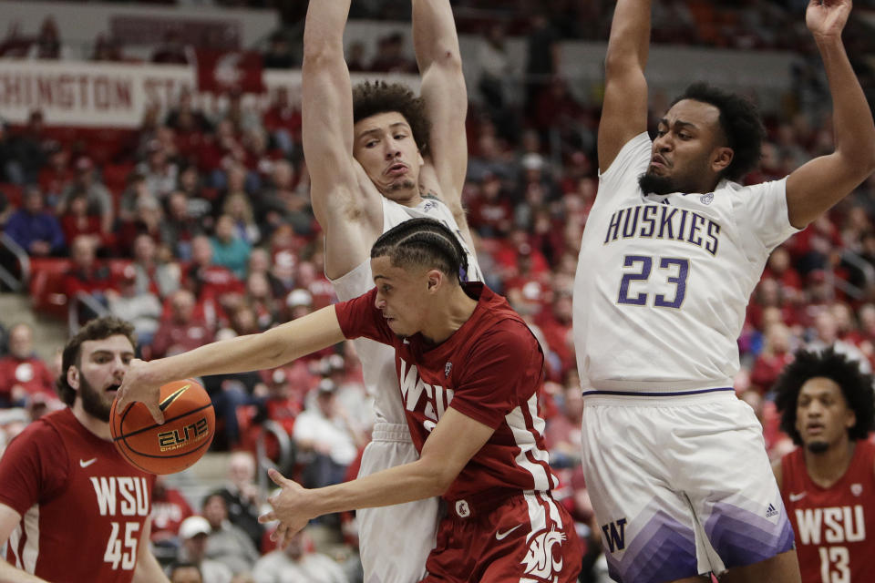 Washington State guard Isaiah Watts, front center, passes the ball while pressured by Washington guard Anthony Holland (23) and center Braxton Meah, top center, during the first half of an NCAA college basketball game, Thursday, March 7, 2024, in Pullman, Wash. (AP Photo/Young Kwak)