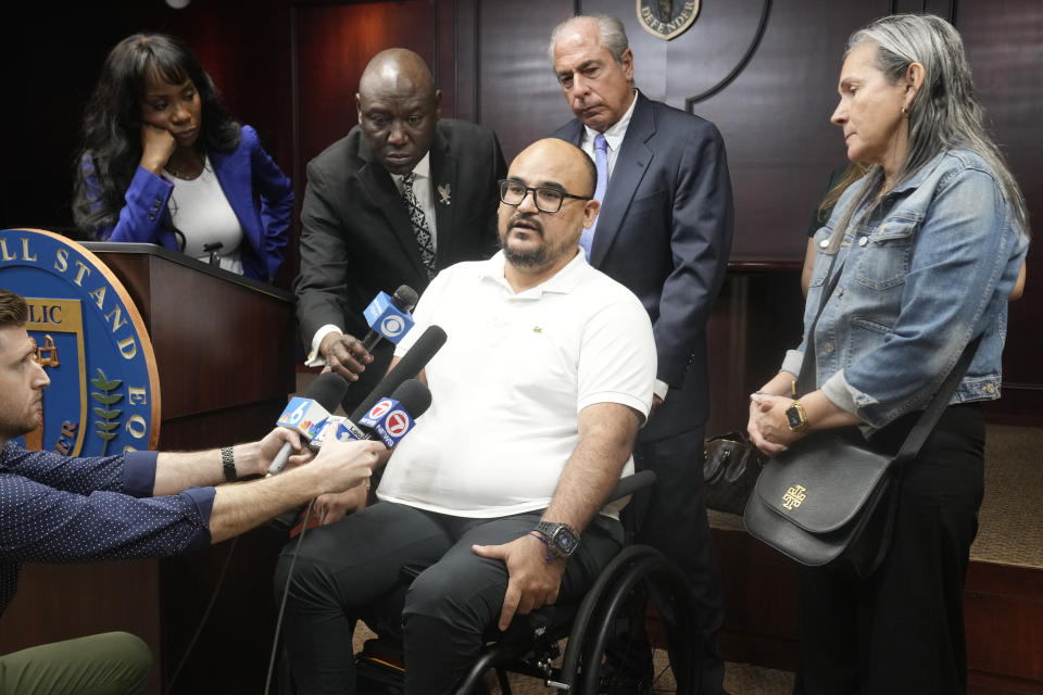 Michael Ortiz speaks at a news conference regarding a lawsuit against a police officer Wednesday, March 1, 2023, in Fort Lauderdale, Fla. Ortiz is suing after being paralyzed by a Hollywood, Fla., police officer who mistook his handgun for a taser and shot him in the back. Behind Ortiz are attorneys Ben Crump and Hunter Shkolnik. His mother Betty Ortiz is at right. (AP Photo/Marta Lavandier)