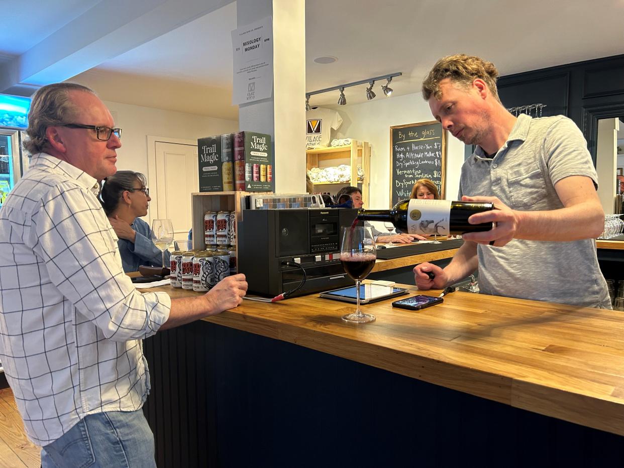 Adam Fleischer, right, pours a glass of wine for Jon Barrett during a tasting event Wednesday at Village Wine Company. The shop, which opened in February, offers a different kind of shopping experience where customers can leave with wine tailored for them.