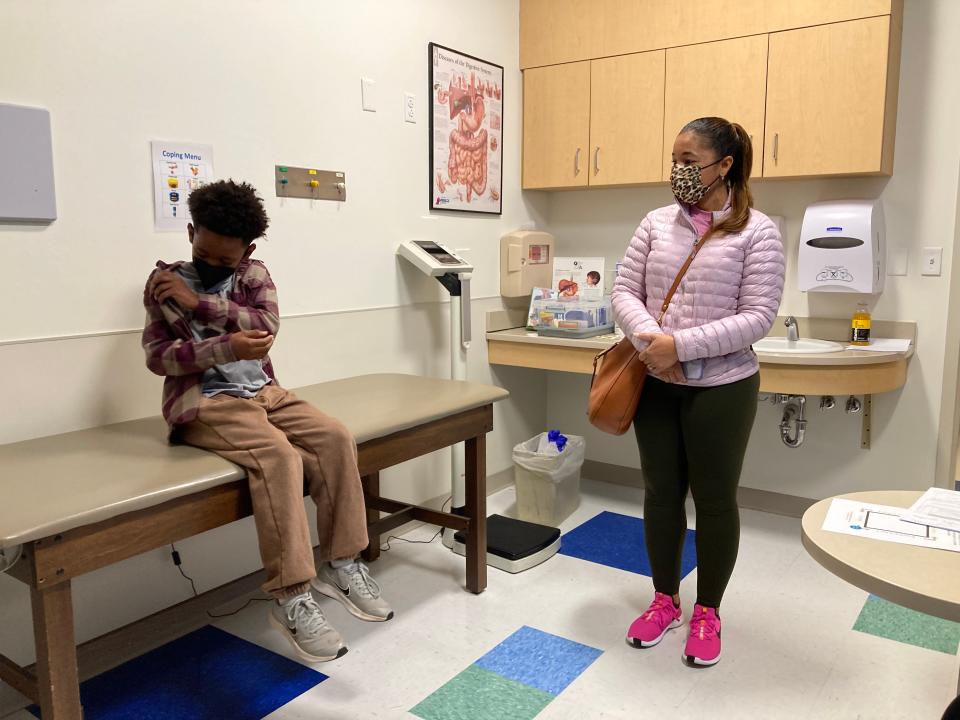 Danielle Simmonds watches her son, Michael, take off his jacket in preparation of his first dose of the pediatric COVID-19 vaccine.