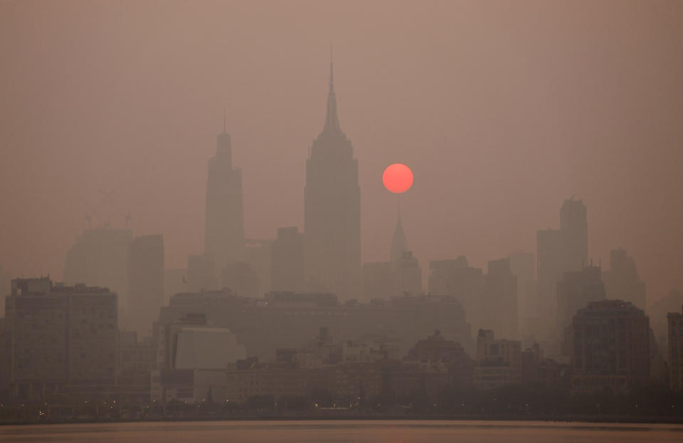 The sun is shrouded as it rises in a smokey sky behind the Empire State Building in New York City on June 8, 2023, as seen from Jersey City, New Jersey. (Photo by Gary Hershorn/Getty Images)